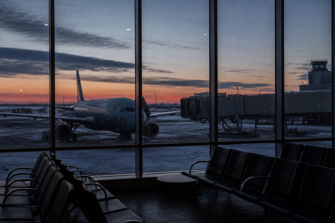 Quiet airport gate with snow falling outside the window and a single aircraft on the stand