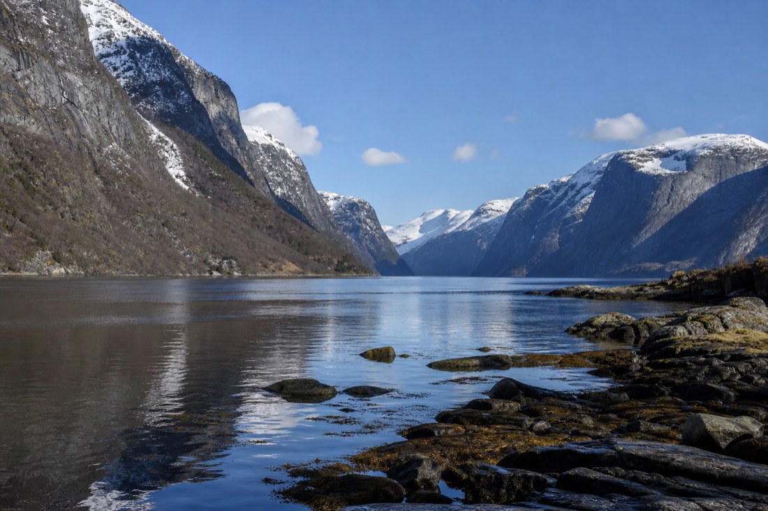 Clear spring morning on a Norwegian fjord with snow still on the high peaks and calm reflective water