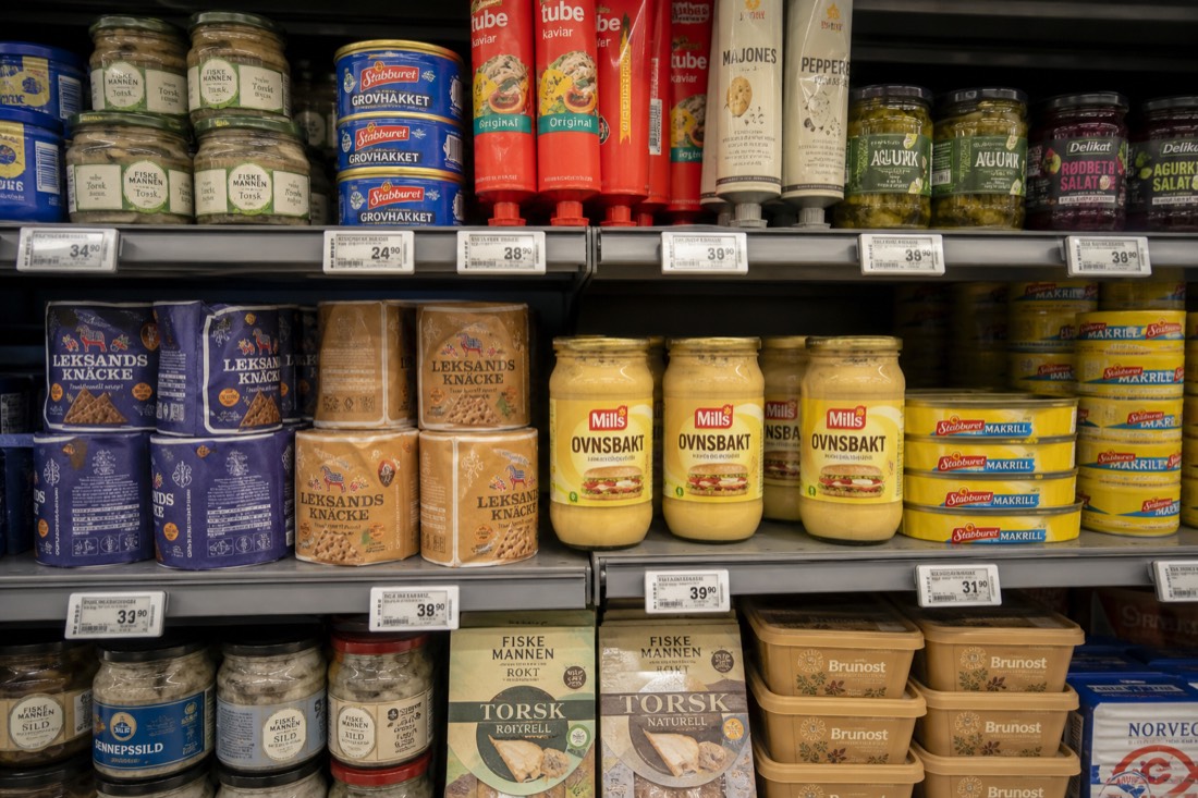Supermarket shelf of Norwegian groceries with price labels in kroner under bright store lighting