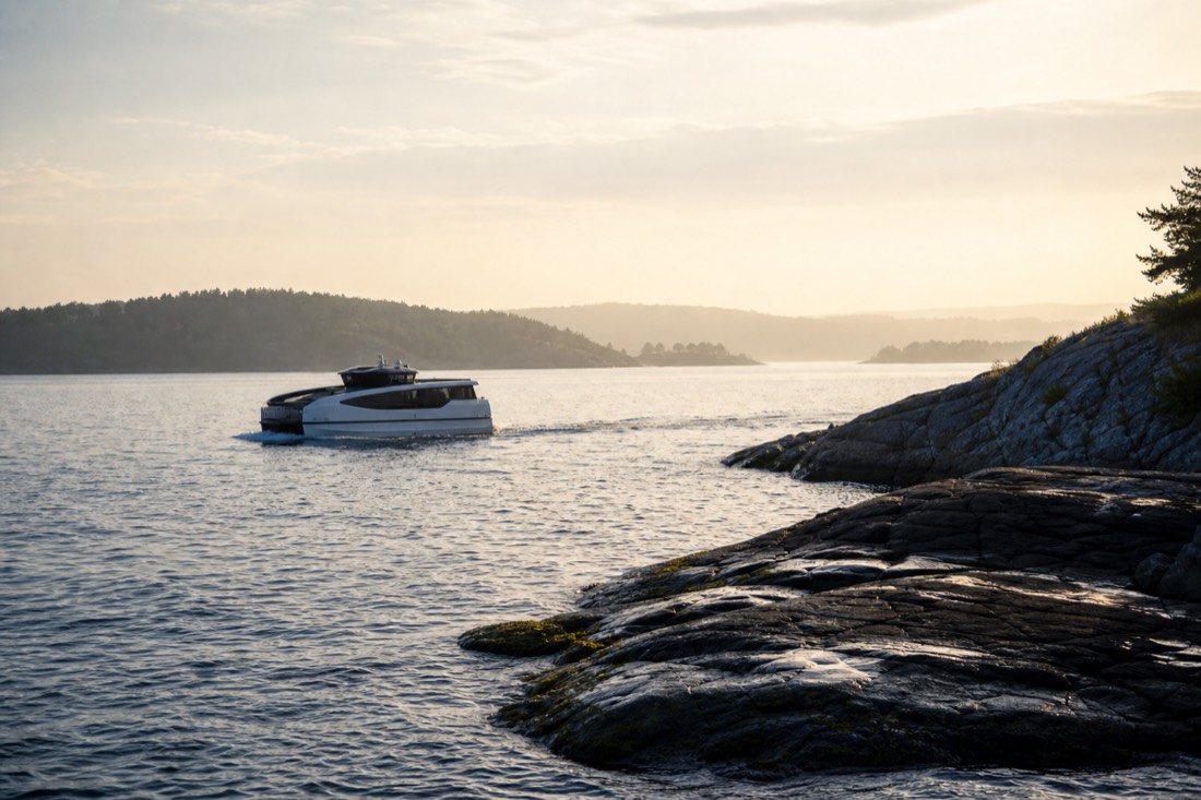 Electric passenger boat gliding silently across the Oslofjord past low forested islands at golden hour