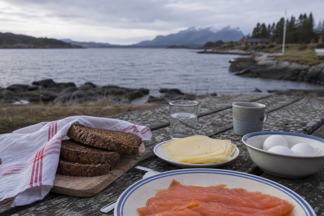 Norwegian breakfast table with dark rye bread, sliced cheese, cured salmon and boiled eggs