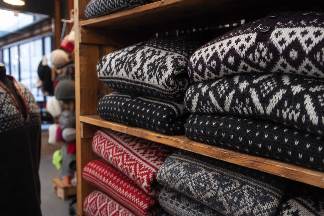 Folded traditional patterned Norwegian wool sweaters stacked on a wooden shop shelf