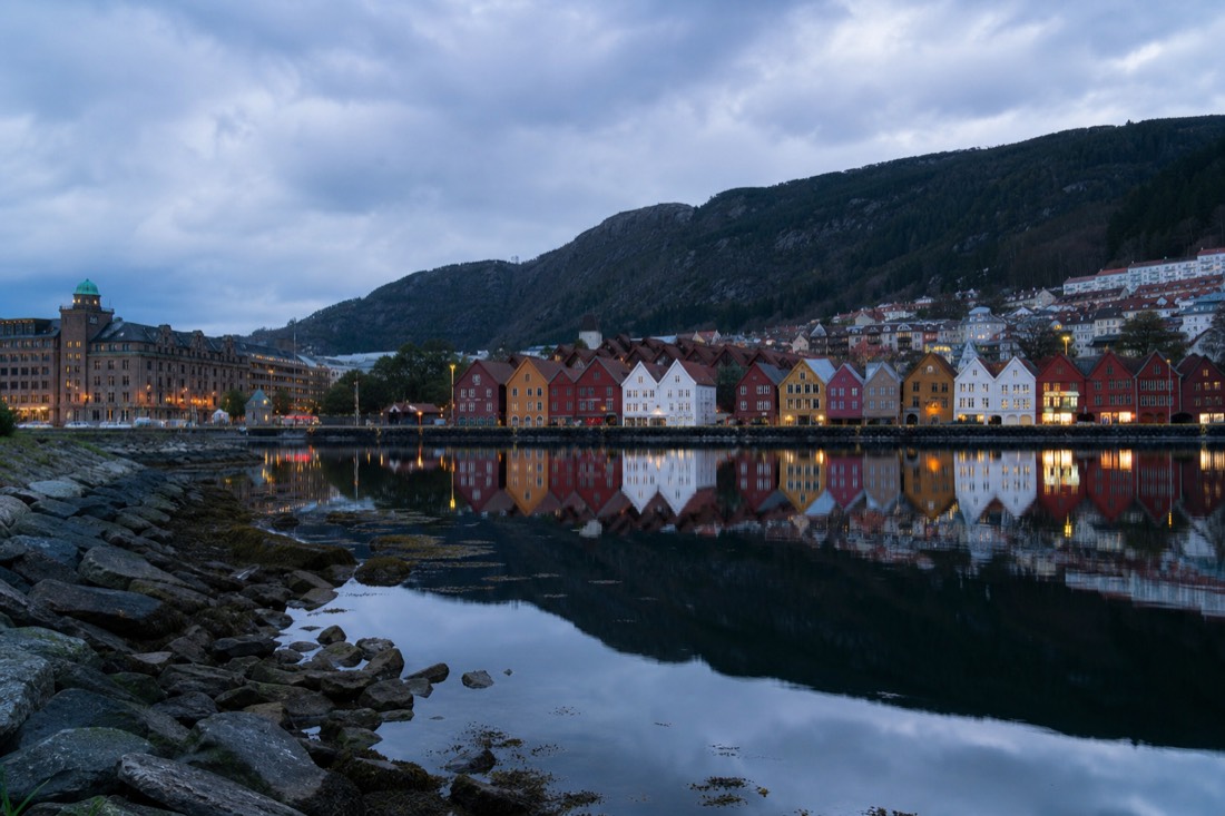 Bergen's Bryggen wharf with its wooden gabled facades reflected in the harbour at dusk