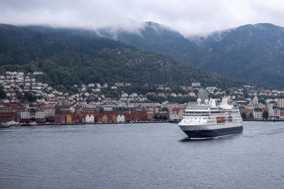 Bergen's harbour with a cruise boat leaving the quay and the seven mountains rising behind the city