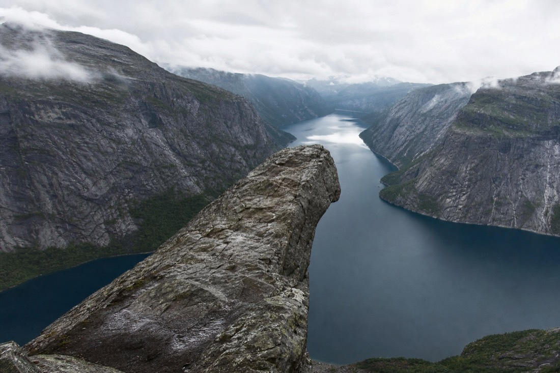 Narrow rock tongue projecting out over a long mountain lake with steep grey slopes on both sides