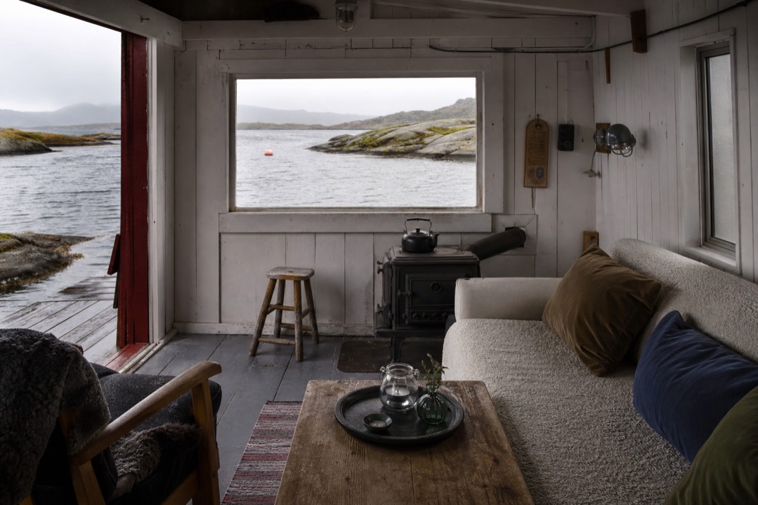 Interior of a converted red fishing cabin with wooden walls and a window facing the water