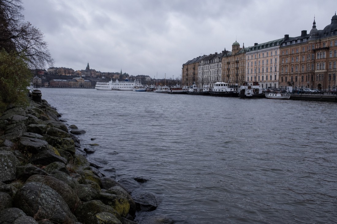 Wide river running through a Scandinavian capital with waterfront buildings and moored boats