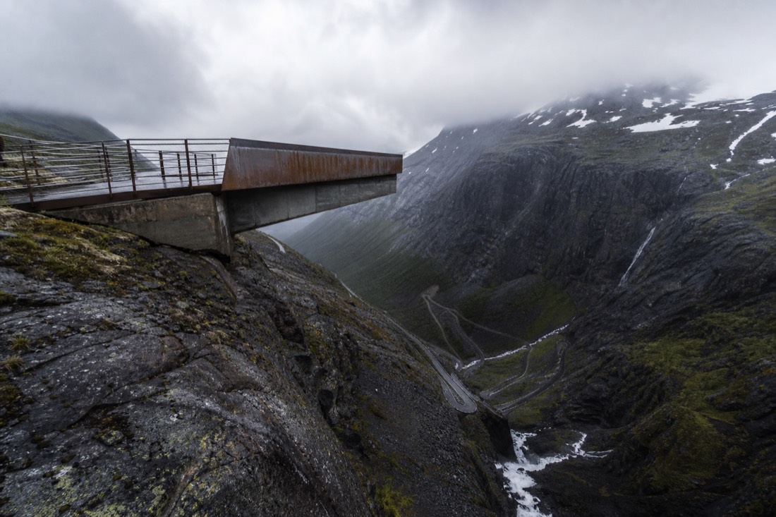 Viewing platform of steel and concrete cantilevered over a mountain valley with switchback road below