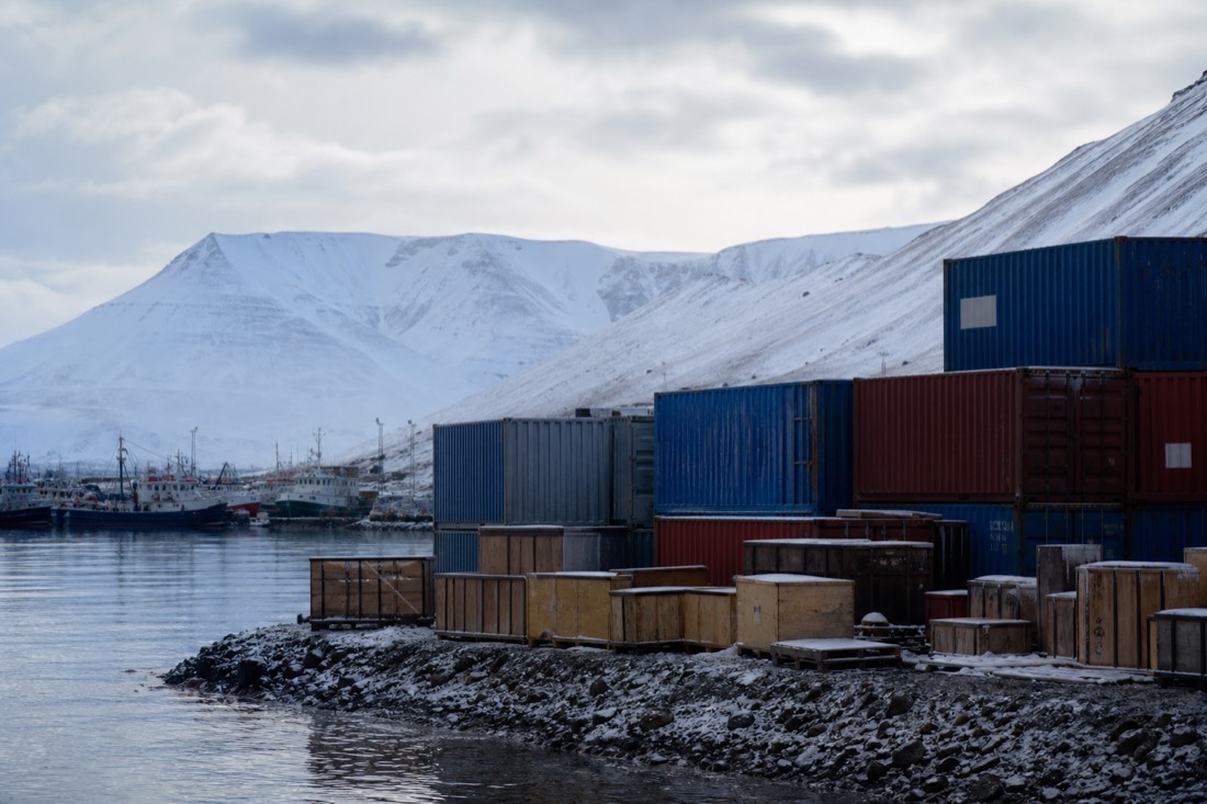 Wooden supply crates and snow-dusted shipping containers at Longyearbyen harbour with mountains behind