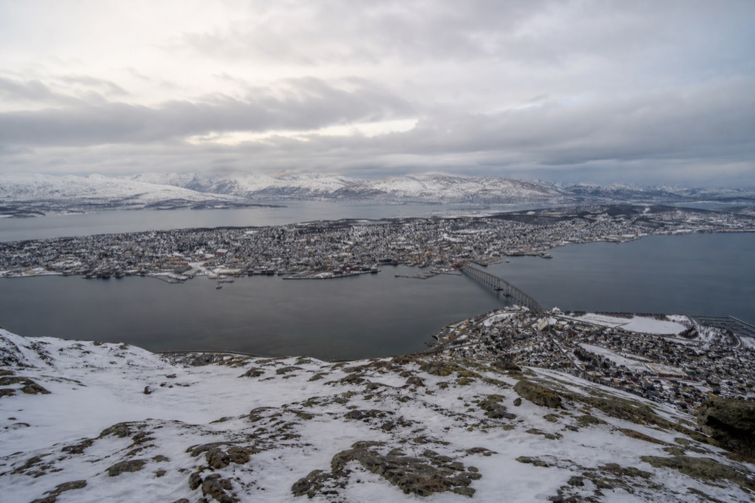 View from Storsteinen platform over snow-covered Tromsø island, the bridge and dark fjord water below